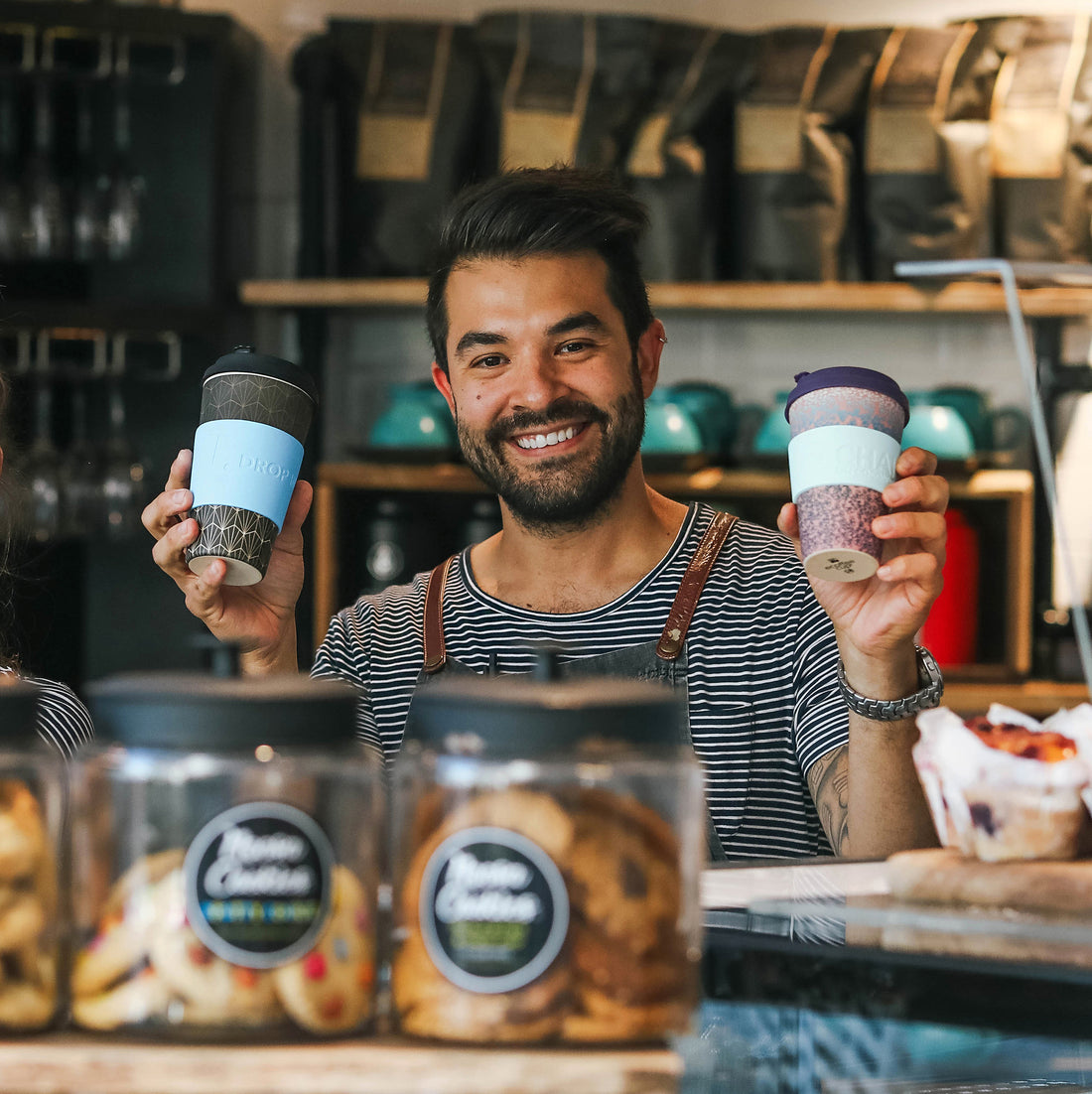 barista holding reusable Coffee Cuff cup with name and coffee order on keep cups