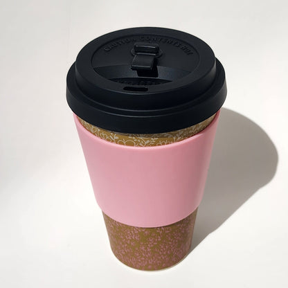 Pink coffee cup with a black lid on a white background