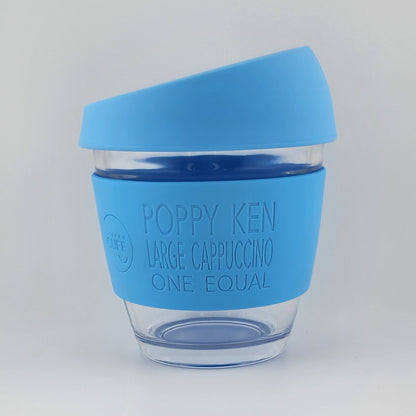 A reusable coffee cup with a bright blue silicone sleeve and matching blue lid, shown on a plain light gray background. The sleeve is printed with the brand name 'POPPY KEN' and the text 'LARGE CAPPUCCINO ONE EQUAL'.