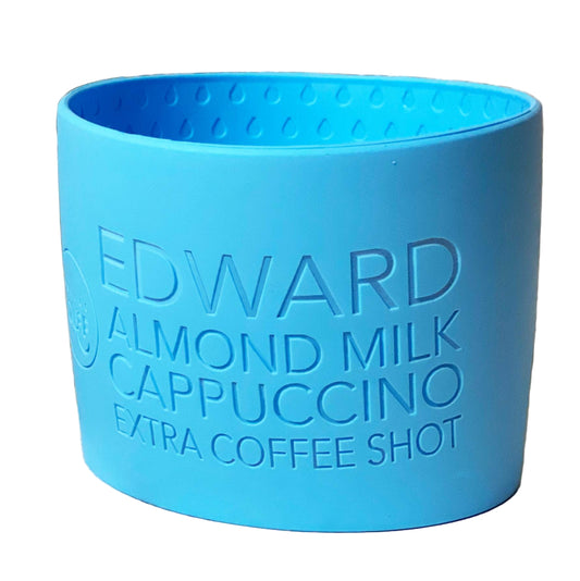 A blue reusable cup cuff with custom text 'EDWARD ALMOND MILK CAPPUCCINO EXTRA COFFEE SHOT' embossed